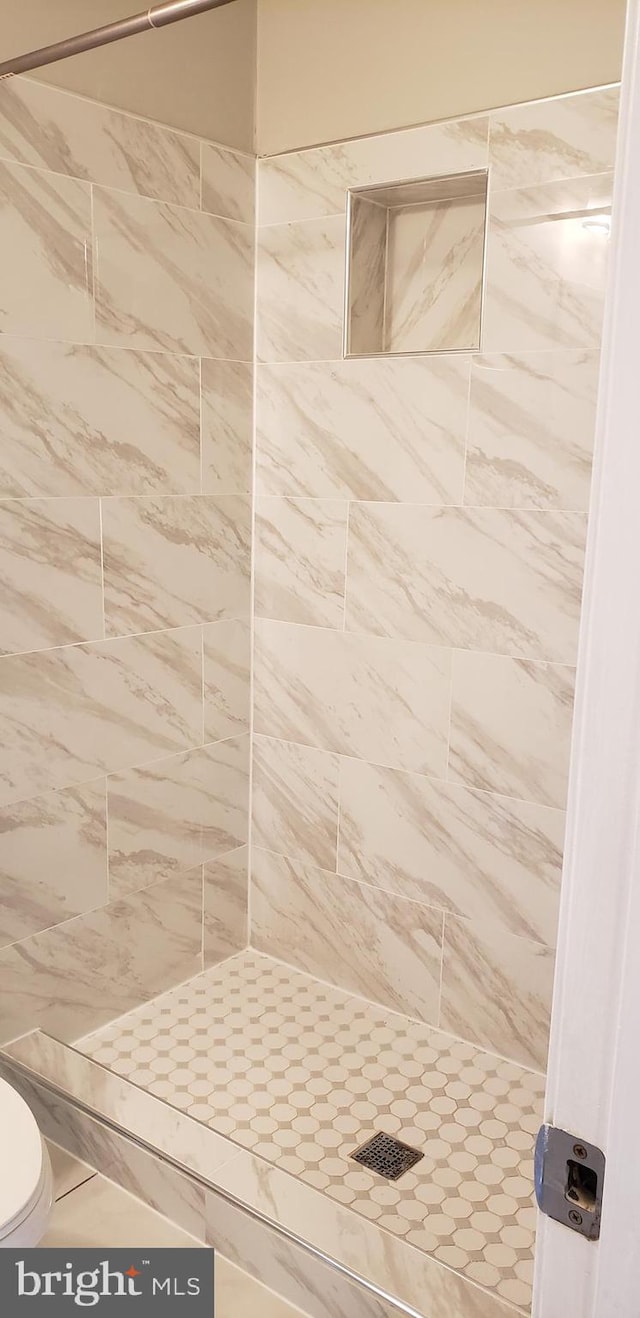 bathroom featuring a tile shower and toilet