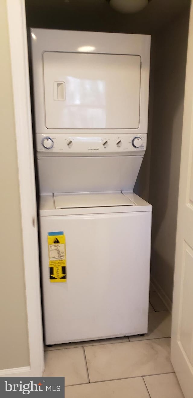 laundry room featuring light tile patterned floors and stacked washer and clothes dryer