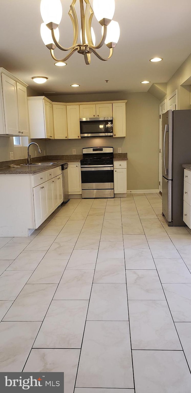 kitchen with pendant lighting, white cabinets, sink, appliances with stainless steel finishes, and a notable chandelier