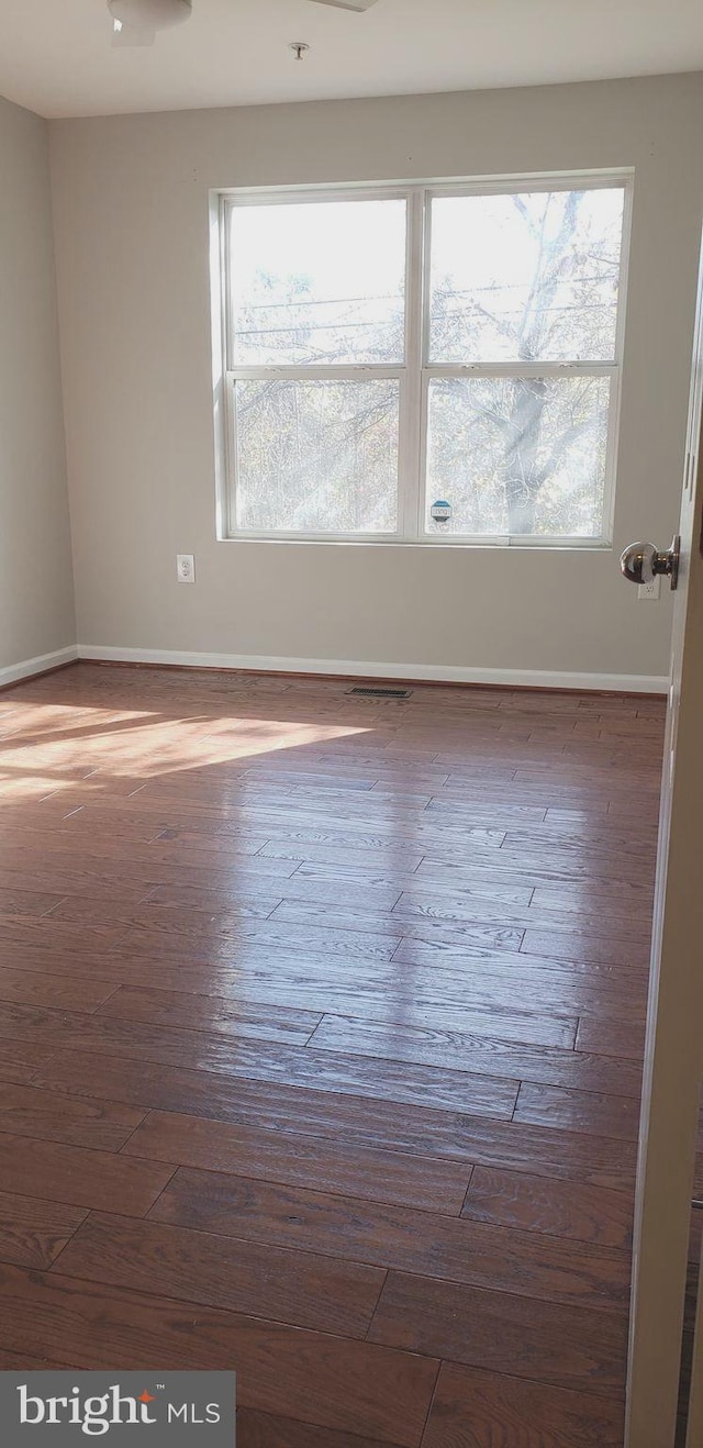 unfurnished room featuring plenty of natural light and dark wood-type flooring