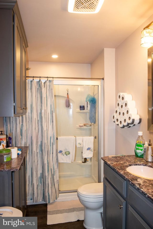 bathroom featuring tasteful backsplash, walk in shower, vanity, hardwood / wood-style flooring, and toilet