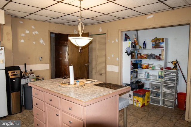 kitchen featuring pendant lighting, tile counters, a kitchen bar, and dark tile patterned floors