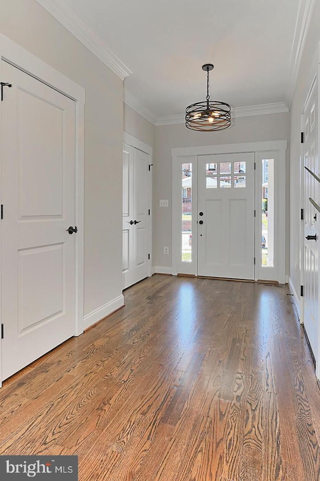 entrance foyer featuring a chandelier, ornamental molding, a healthy amount of sunlight, and hardwood / wood-style flooring