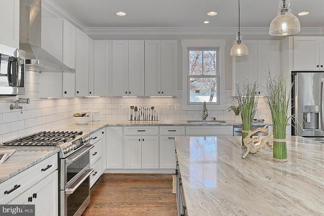 kitchen with white cabinetry, sink, stainless steel appliances, and wall chimney range hood