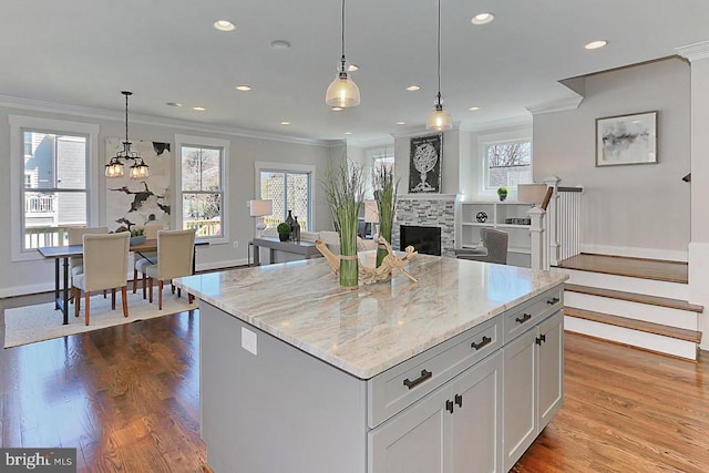 kitchen with a center island, a healthy amount of sunlight, a stone fireplace, and white cabinetry