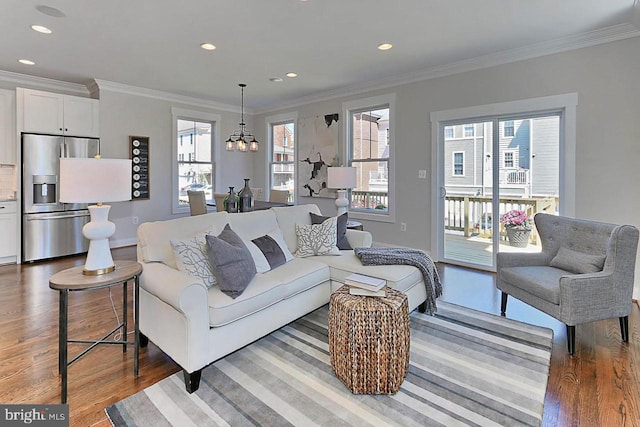 living room with hardwood / wood-style floors, crown molding, and a notable chandelier