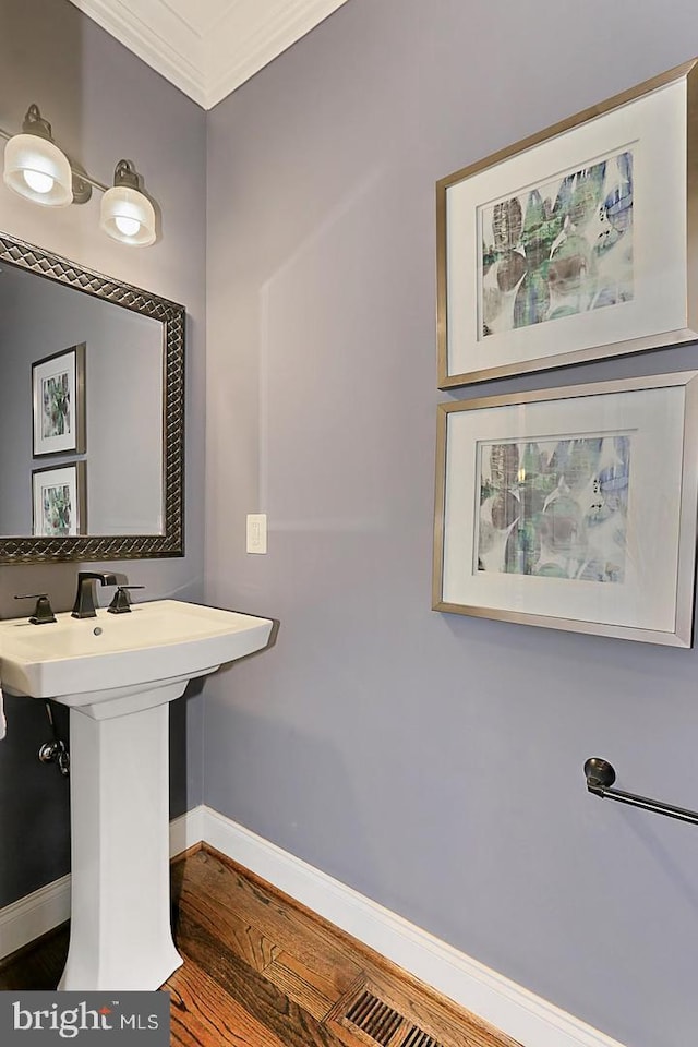 bathroom with hardwood / wood-style floors, crown molding, and sink