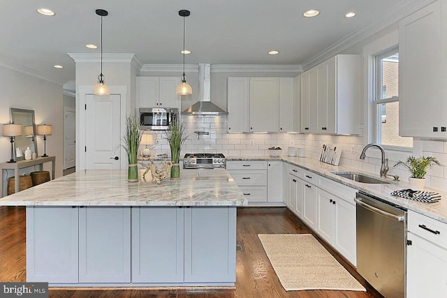 kitchen featuring appliances with stainless steel finishes, wall chimney exhaust hood, sink, white cabinets, and a center island