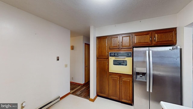 kitchen featuring stainless steel refrigerator with ice dispenser, light wood-type flooring, white oven, a textured ceiling, and a baseboard radiator