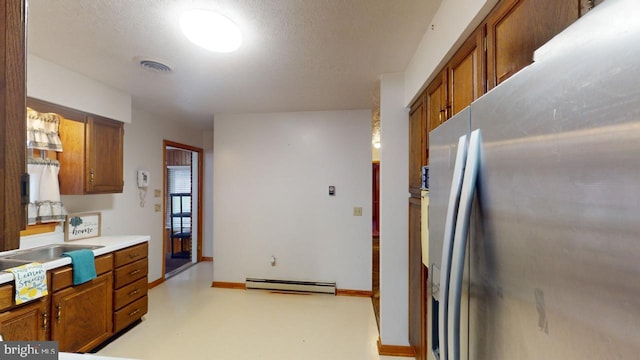 kitchen featuring stainless steel fridge, a textured ceiling, and a baseboard radiator