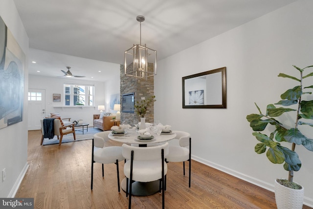 dining area with wood-type flooring and ceiling fan with notable chandelier