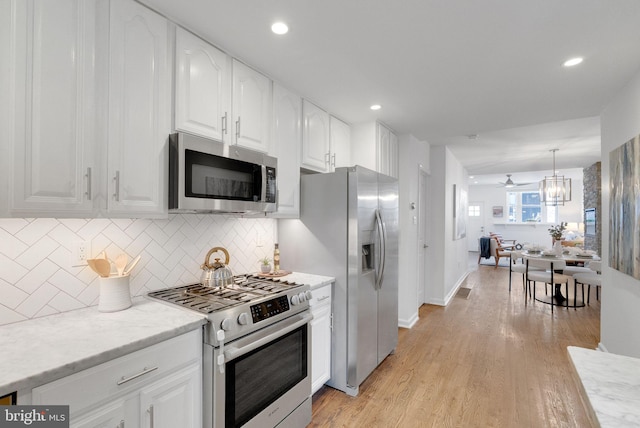 kitchen with white cabinetry, ceiling fan, pendant lighting, light hardwood / wood-style floors, and appliances with stainless steel finishes