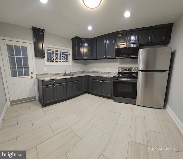 kitchen featuring light stone countertops, stainless steel appliances, and sink