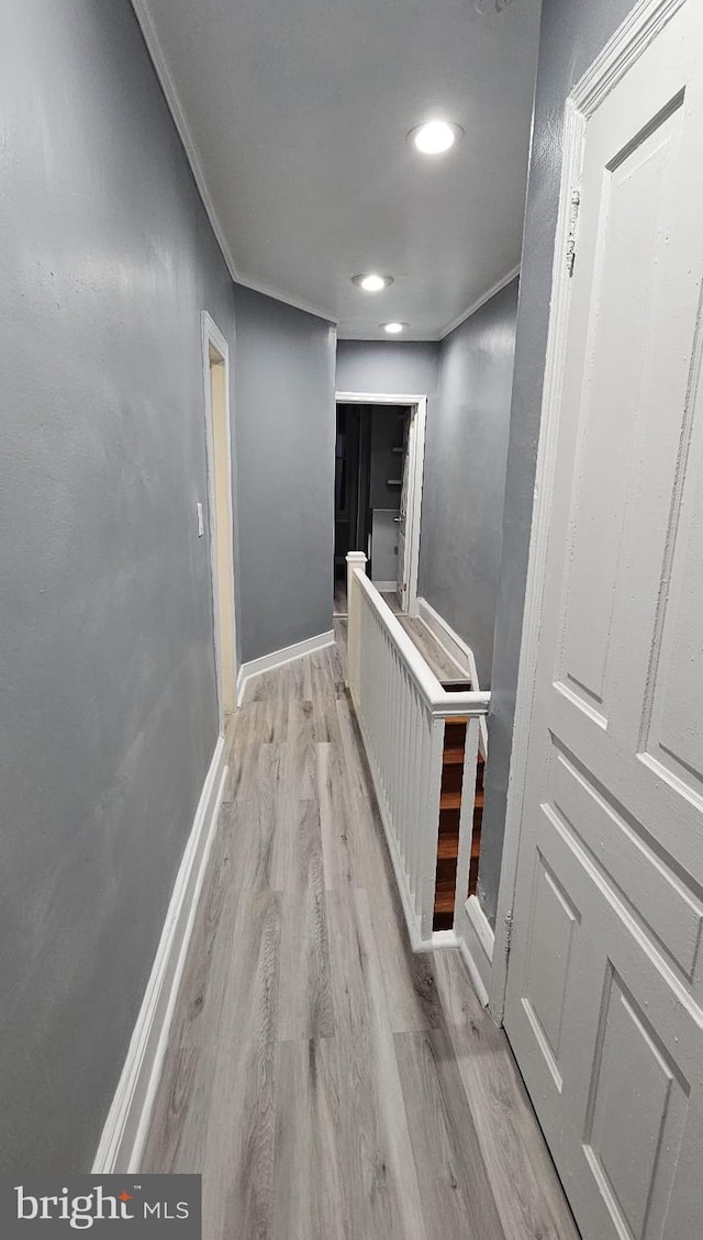 hallway with light hardwood / wood-style floors and crown molding