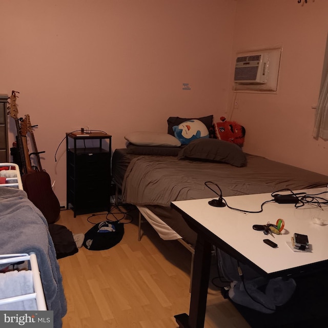 bedroom with a wall mounted air conditioner and wood-type flooring