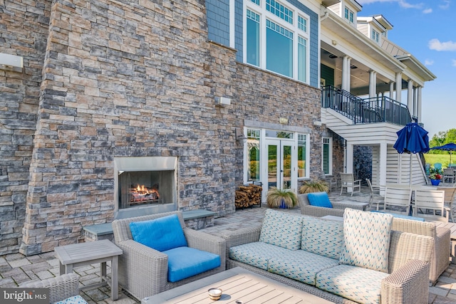 view of patio / terrace with a balcony and an outdoor stone fireplace