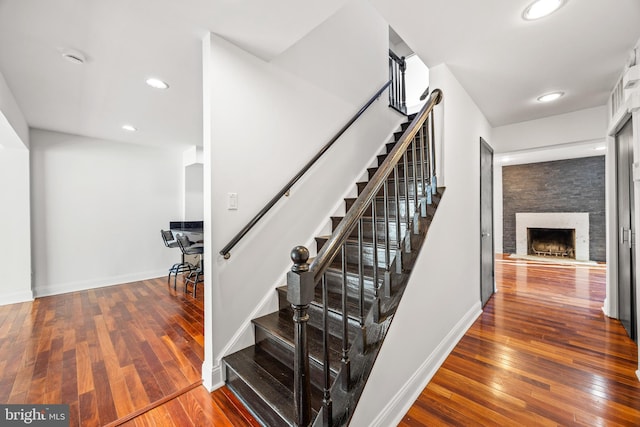 stairs with wood-type flooring and a fireplace