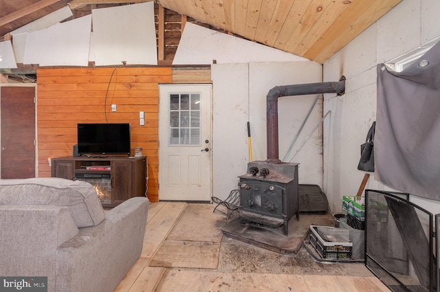 living room featuring a wood stove, wooden walls, wooden ceiling, and vaulted ceiling