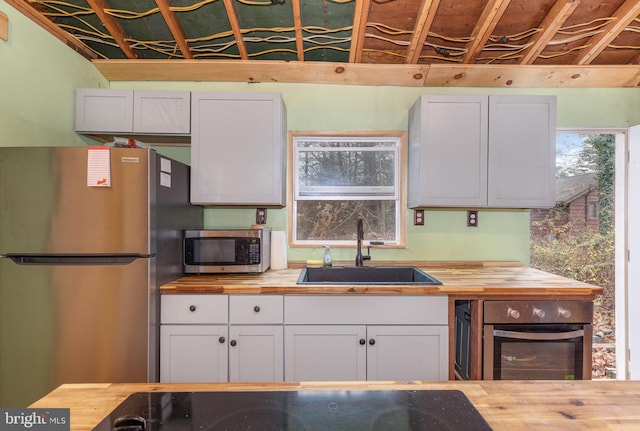 kitchen featuring appliances with stainless steel finishes, white cabinetry, butcher block counters, and sink