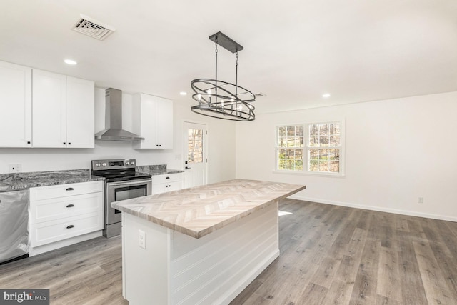 kitchen featuring wall chimney range hood, hanging light fixtures, light hardwood / wood-style flooring, white cabinetry, and stainless steel appliances