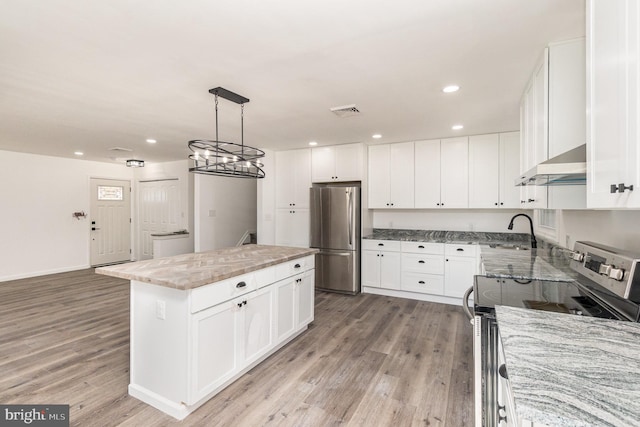 kitchen featuring white cabinets, appliances with stainless steel finishes, a kitchen island, and exhaust hood