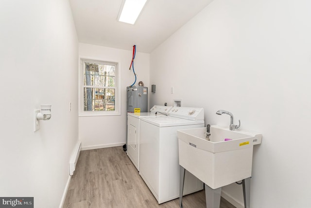 laundry room featuring electric water heater, light hardwood / wood-style floors, separate washer and dryer, and sink