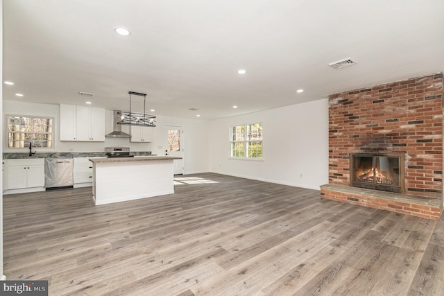 unfurnished living room featuring a fireplace, light wood-type flooring, and sink