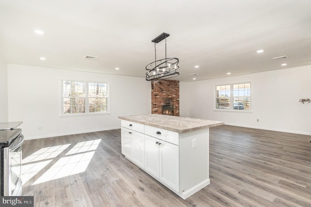 kitchen featuring white cabinets, a center island, a healthy amount of sunlight, and light hardwood / wood-style floors