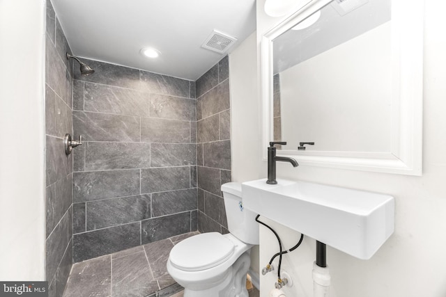 bathroom featuring tiled shower and toilet