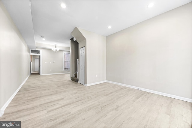 unfurnished living room with a notable chandelier and light wood-type flooring