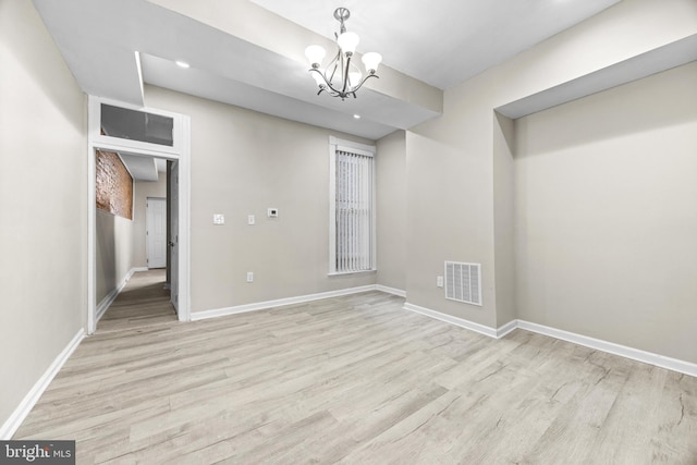 spare room featuring light hardwood / wood-style floors and a notable chandelier