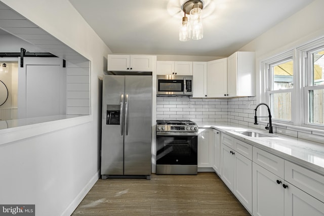 kitchen with light hardwood / wood-style floors, a barn door, white cabinetry, and appliances with stainless steel finishes