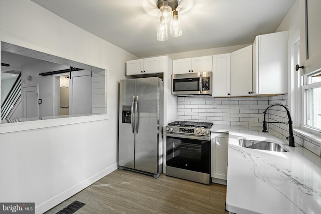 kitchen featuring white cabinets, a barn door, stainless steel appliances, and sink