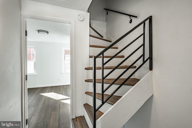 stairway with hardwood / wood-style floors and a textured ceiling