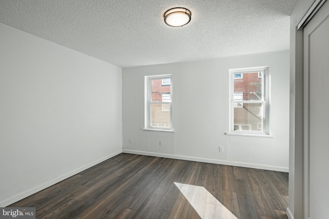 unfurnished room with a textured ceiling and dark wood-type flooring