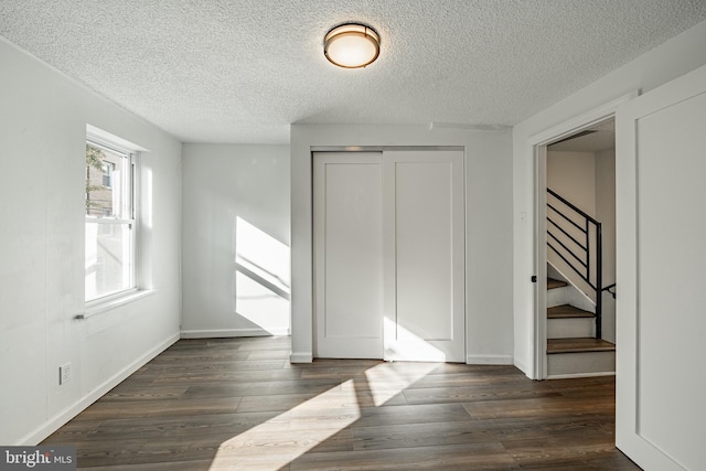 interior space with a textured ceiling, dark hardwood / wood-style floors, and a closet