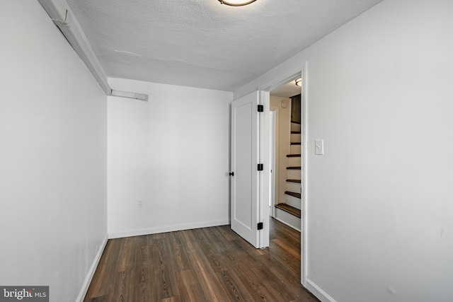 hallway featuring a textured ceiling and dark wood-type flooring