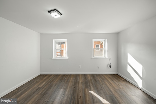 spare room with a wealth of natural light and dark wood-type flooring