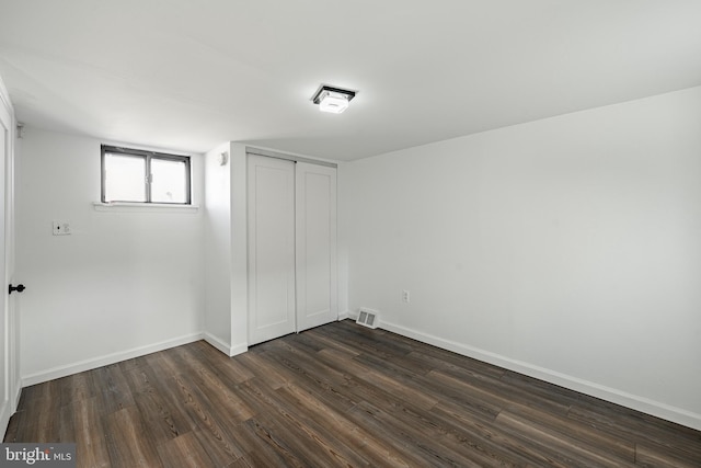 unfurnished bedroom featuring dark hardwood / wood-style flooring and a closet