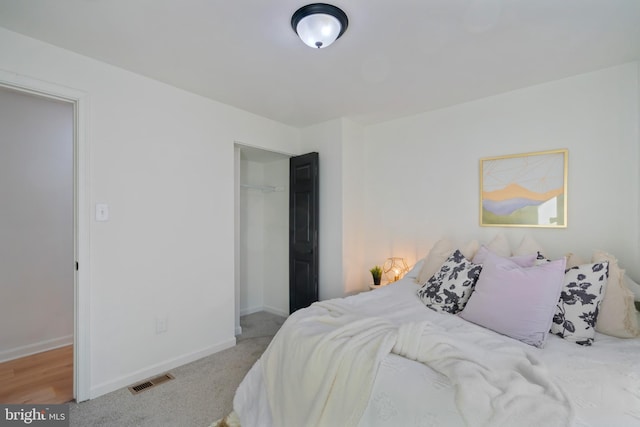 carpeted bedroom with a walk in closet and a closet