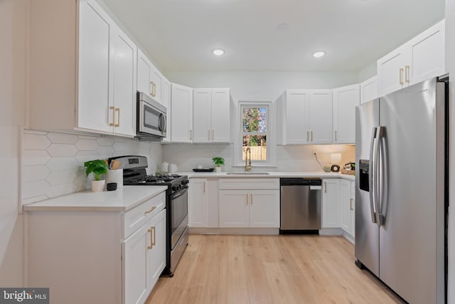 kitchen with sink, light hardwood / wood-style flooring, tasteful backsplash, white cabinetry, and stainless steel appliances