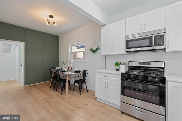 kitchen with backsplash, white cabinetry, light hardwood / wood-style floors, and appliances with stainless steel finishes