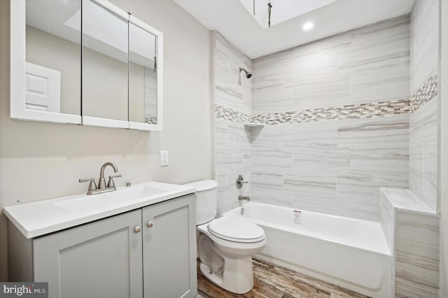 full bathroom featuring vanity, wood-type flooring, tiled shower / bath combo, and toilet