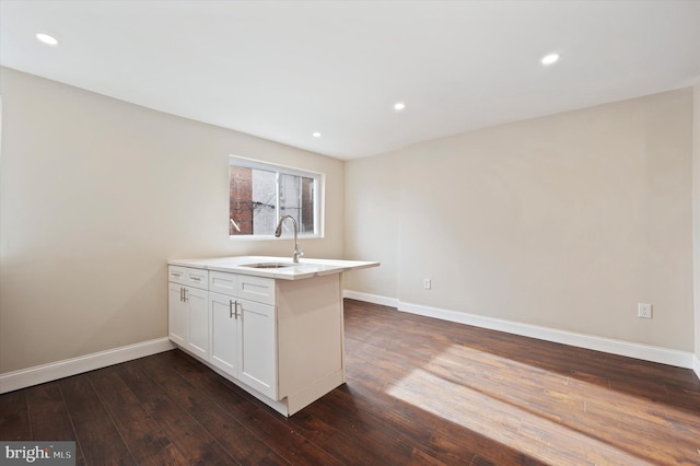 kitchen with kitchen peninsula, white cabinetry, sink, and dark wood-type flooring