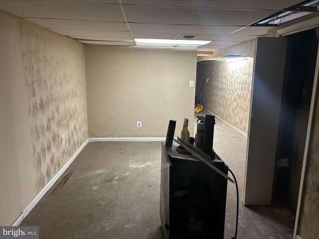 basement with a paneled ceiling and carpet