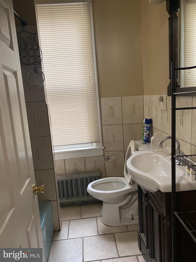 bathroom with radiator, tile patterned floors, toilet, vanity, and tile walls