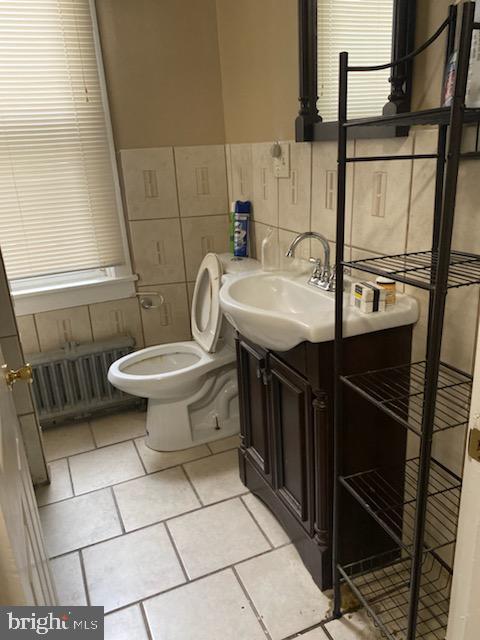 bathroom featuring radiator, vanity, tile walls, tile patterned flooring, and toilet