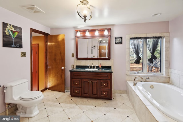 bathroom featuring vanity, a relaxing tiled tub, and toilet