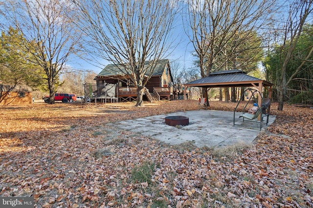 view of yard with a gazebo, a fire pit, a trampoline, and a wooden deck