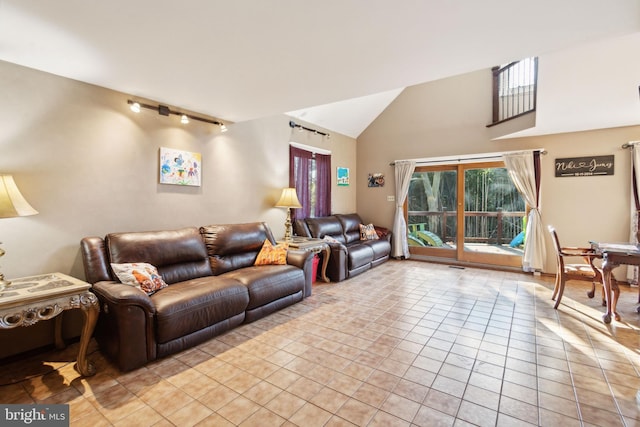 tiled living room featuring rail lighting and high vaulted ceiling